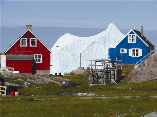 The coloured greenlandic houses with the Disko bay and a giant iceberg in the background