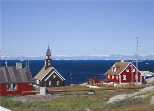 The Zion Church in Ilulissat - the Disko Island is seen in the horizon with the huge Lyngmark glacier on the ridge of the steep basalt mountains  
