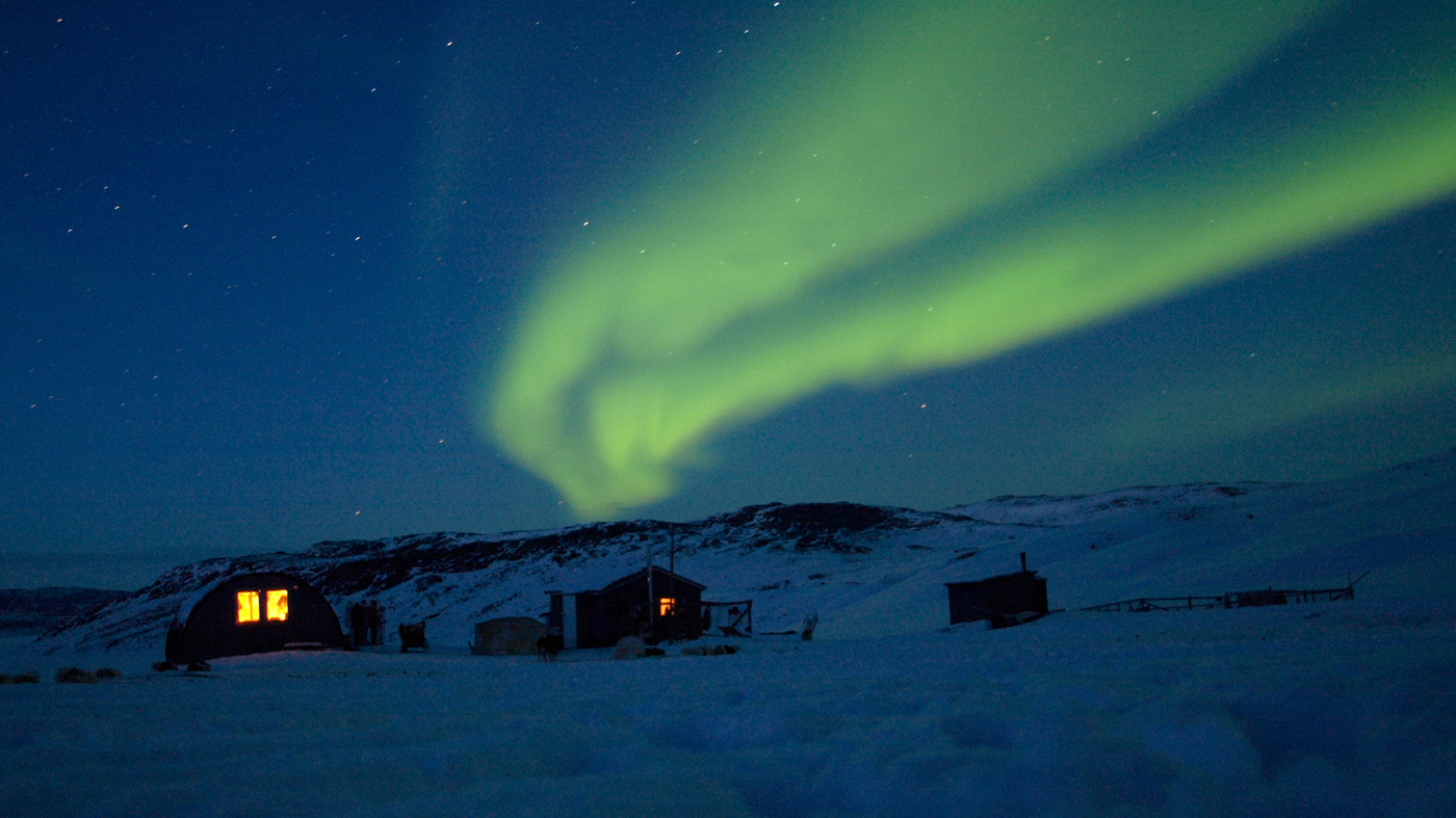 Små hytter med nordlys på himlen.