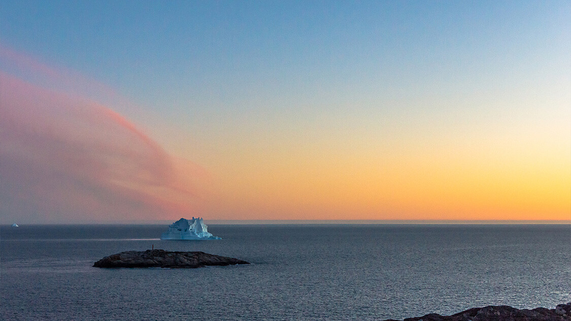 Udsigt over havet med isbjerg og solnedgang