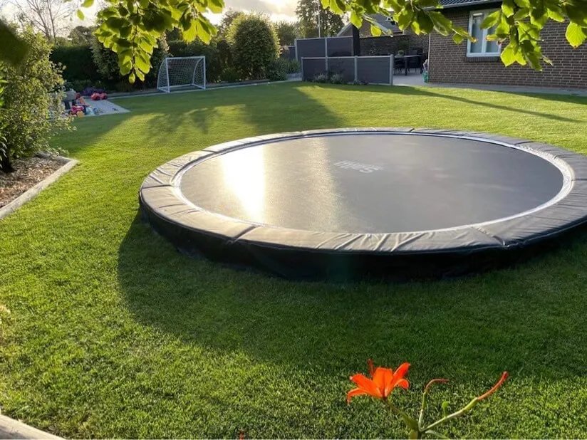 En flot og sund græsplæne med en trampolin.