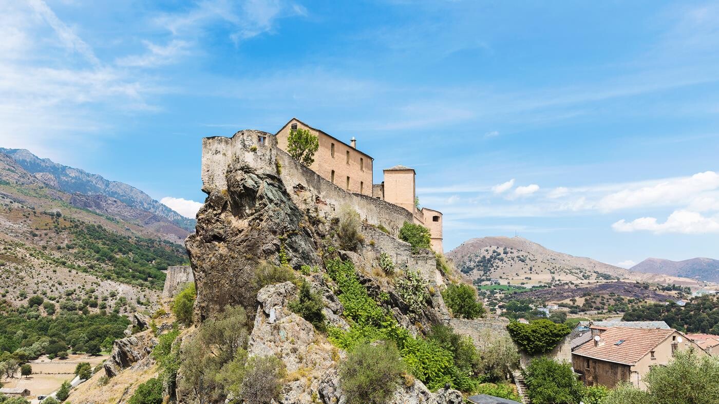 Korsikansk landsby med befæstet villa på toppen af klippe. 