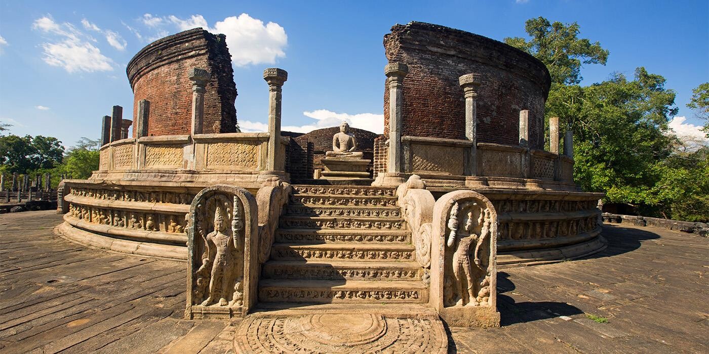 Ruinerne af historiske Polonnaruwa med detajlerede inskiptioner og Buddha-statue i centrum.
