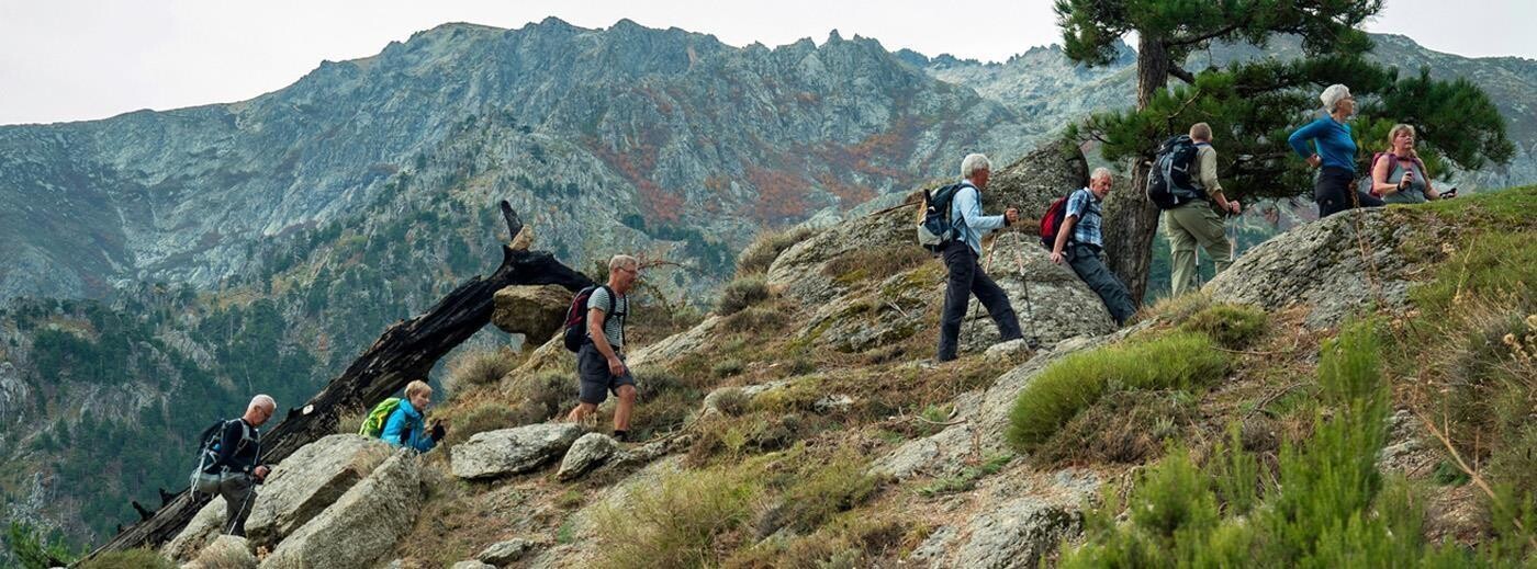 Vandreferie på Korsika - en flok vandrere bevæger sig op ad korsikansk granitklippe, som er dækket af let maki-krat. 