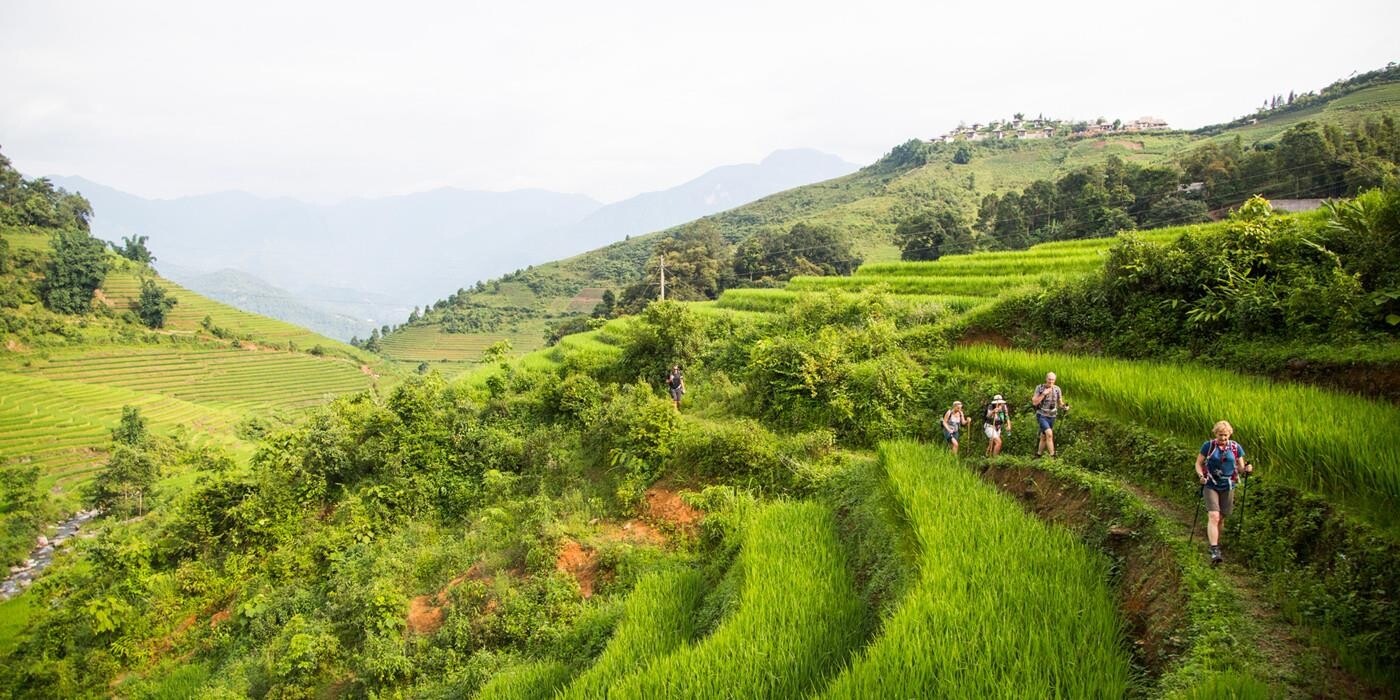 Vandreferie blandt rismarker i Sapa, Vietnam. I baggrunden ses luksuriøse Topas Ecolodge på en bjergtop. 