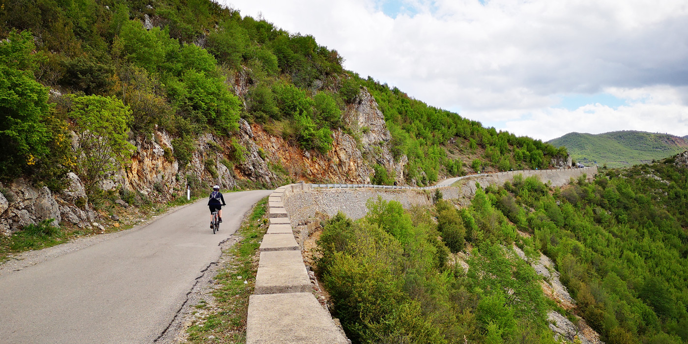 Enkel person cykler langs bjergvej. 
