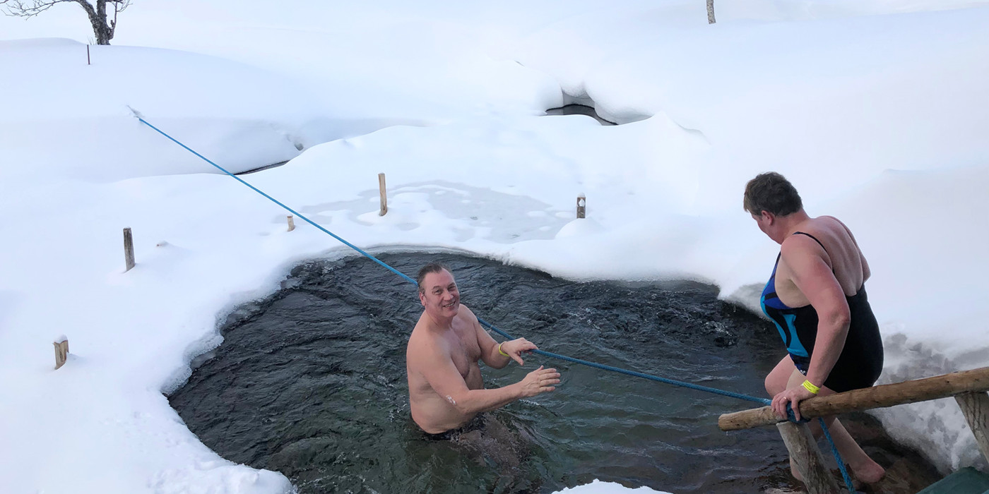 Mand og kvinde bader i hul i isen.
