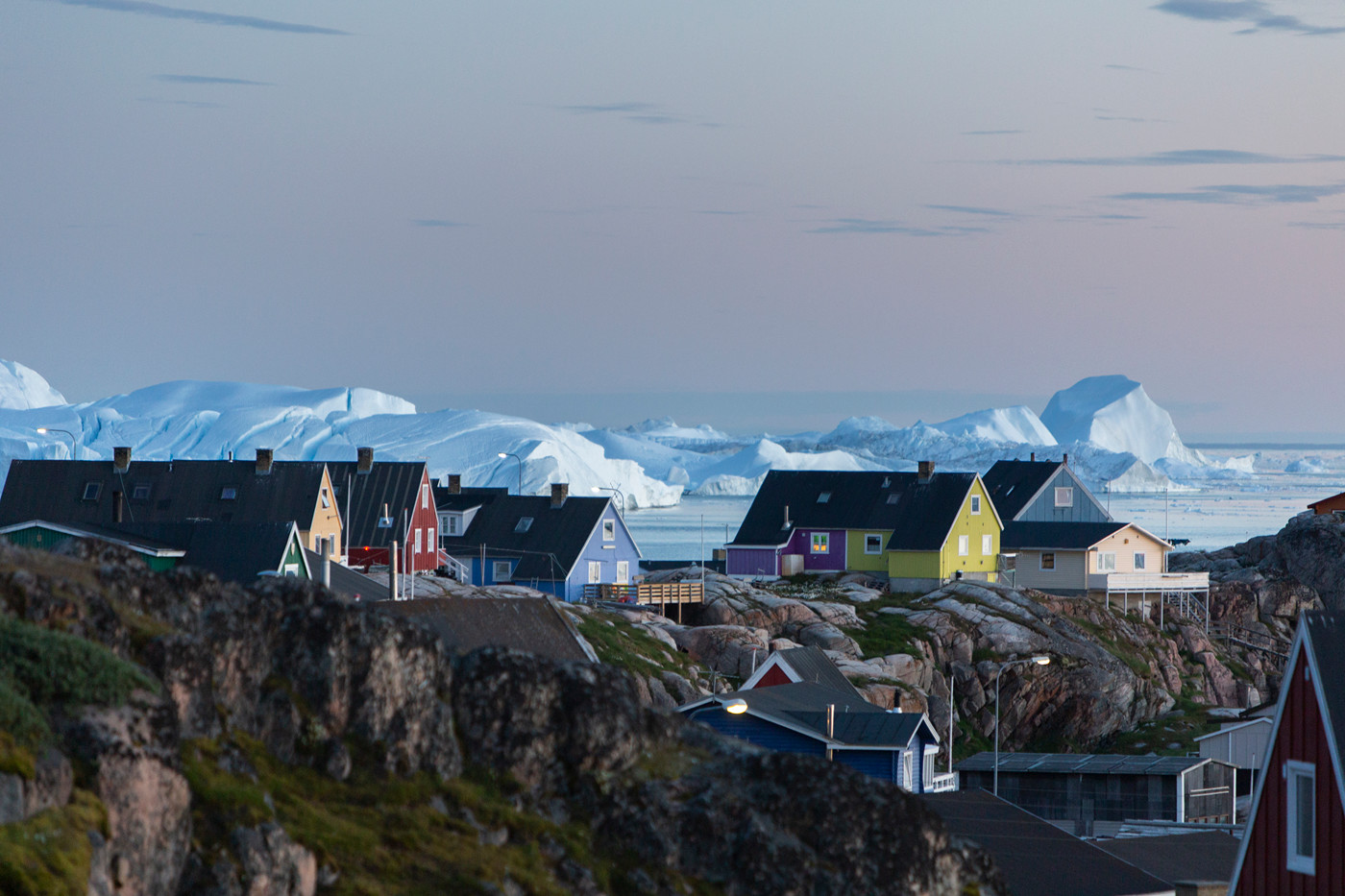Farverige huse i Grønland med isfjorden i baggrunden.