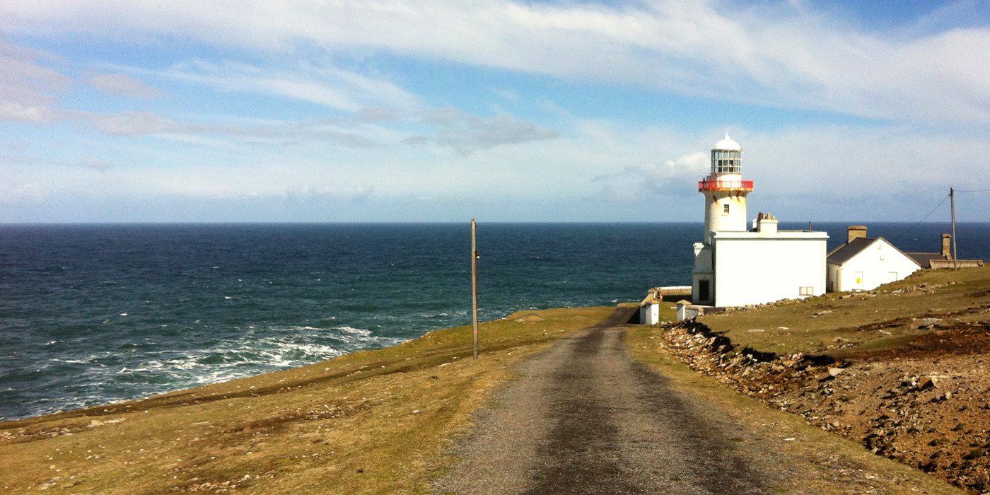Hvidt fyrtårn på kysten af Arranmore Island, med udsigt over havet.