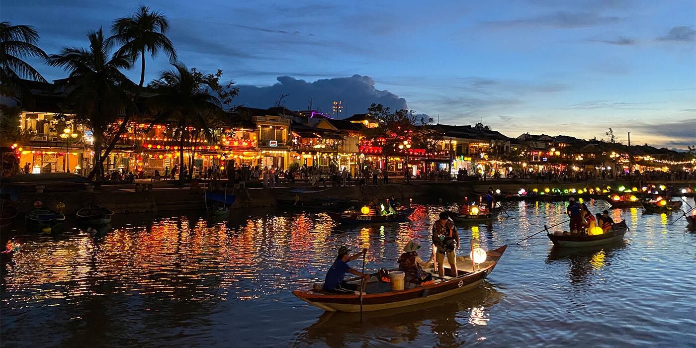 Aftenhimmel og lanterner reflekteres i vandet på flod gennem Hoi An.