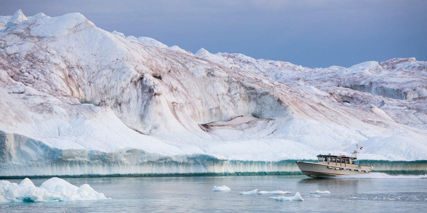 Båd sejler mellem isbjerge.