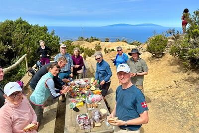 Topas-rejsende samlet ved frokostbordet under vandretur med udsigt til La Palma i horisonten. 