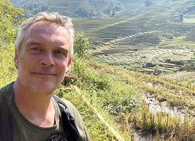 Foto af Peter Knudsen i Sapa, Vietnam, med rismarker i baggrunden.