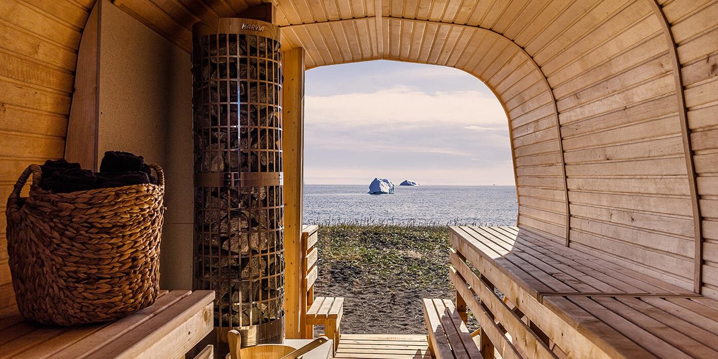 Hotel Disko Islands sauna med udsigt over sortsandsstrand og hav med isbjerge. 