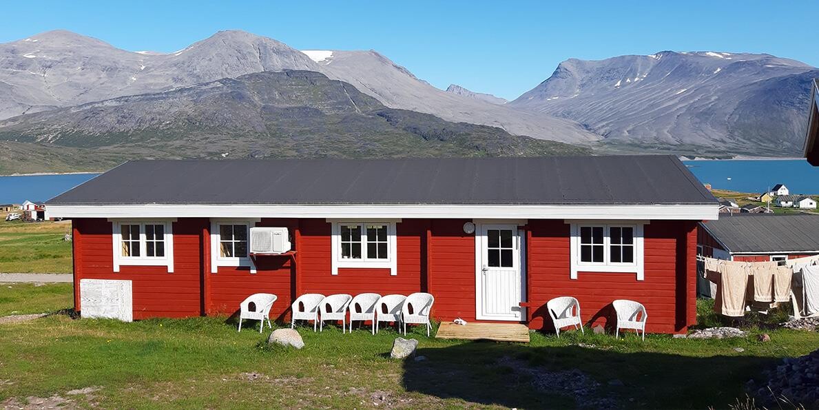 Igaliku Guesthouse with mountains and fiords in the background.
