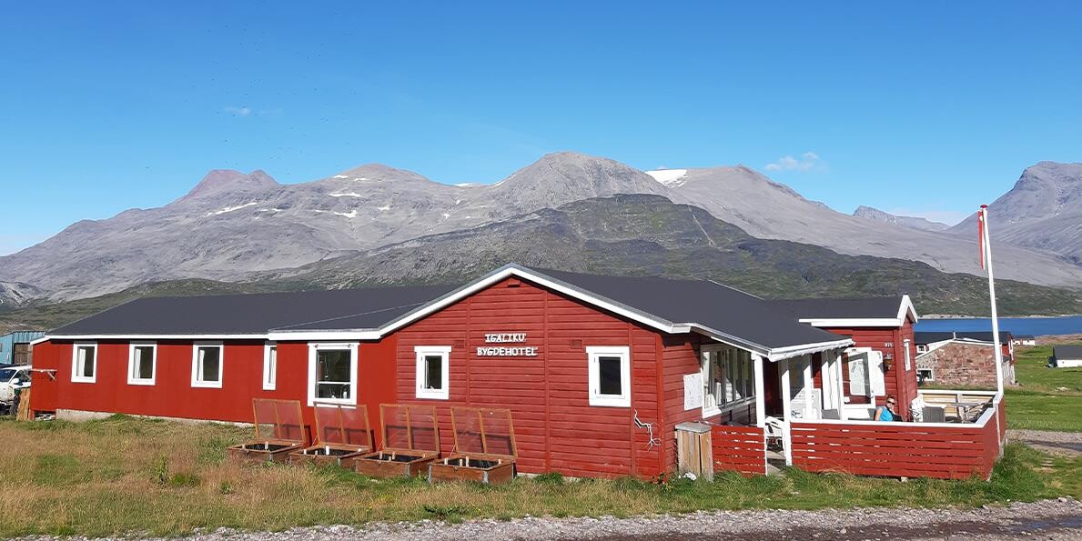 Igaliku bygdehotel med bjerge i baggrunden